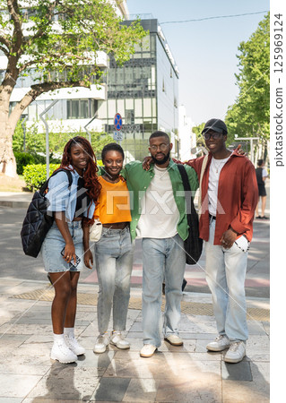 Happy young multicultural group of friends stand together, hugging and smiling at camera on walk 125969124