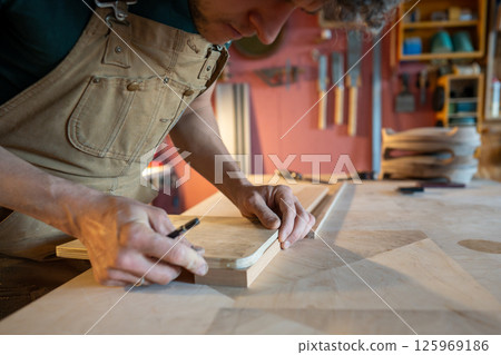 Close up carpenter marking angles and drill positions on wooden board for future furniture piece 125969186