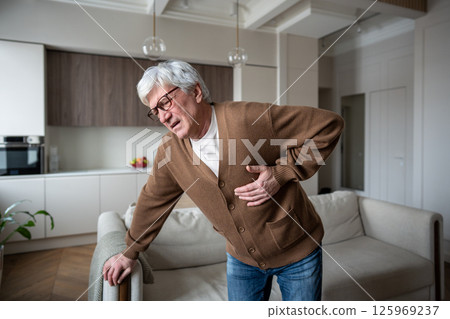 Sudden chest discomfort. Elderly man clutches chest in agony struggling to breathe in heart attack 125969237