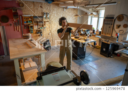 Detail oriented serious craftsman carefully checking timber beam prior to woodworking treatment 125969478