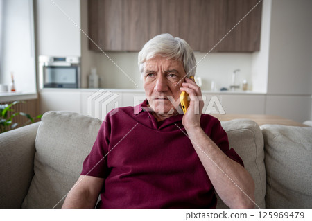 Scared serious senior man show distrust during phone conversation at home, fraud attempt concern 125969479