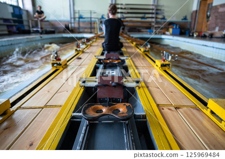 Elite paddlers practice synchronized strokes on row simulator boat for aquatic competition in pool 125969484