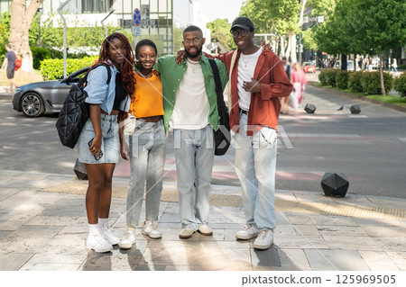 Happy young multicultural group of friends stand together, hugging and smiling at camera on walk 125969505