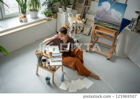 Top view pensive girl contemplate painting idea, working with watercolors and palette in art studio 125969507