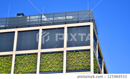 Green office building with plants on the facade. Ecology and green living in city, urban environment concept. Eco architecture. Green office building with plants on the facade. Ecology and green living in city, urban environment concept. Eco architecture. 125969533