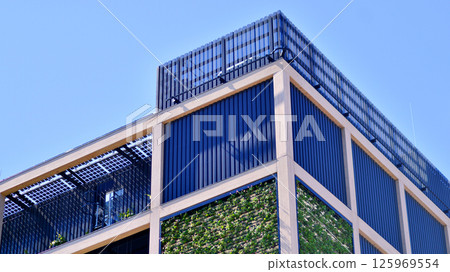 Green office building with plants on the facade. Ecology and green living in city, urban environment concept. Eco architecture. Green office building with plants on the facade. Ecology and green living in city, urban environment concept. Eco architecture. 125969554