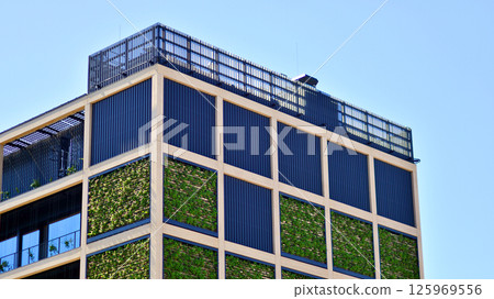 Green office building with plants on the facade. Ecology and green living in city, urban environment concept. Eco architecture. Green office building with plants on the facade. Ecology and green living in city, urban environment concept. Eco architecture. 125969556