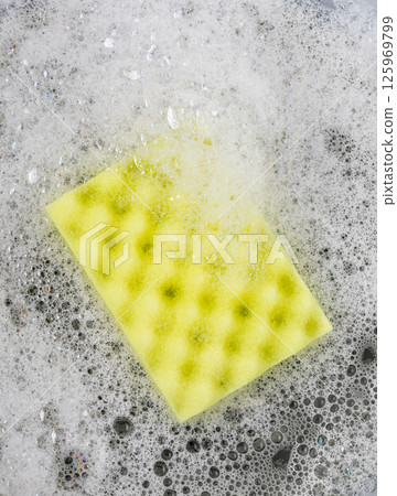 Yellow cleaning sponge soaking in soapy water 125969799
