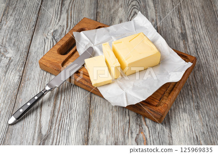 Butter slices with butter knife on wooden cutting board Butter slices with butter knife on wooden cutting board 125969835