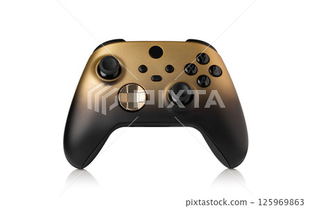 Black and gold video game controller resting on white background 125969863