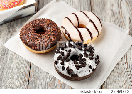 Delicious assorted donuts lying on white plate on wooden table Delicious assorted donuts lying on white plate on wooden table 125969880