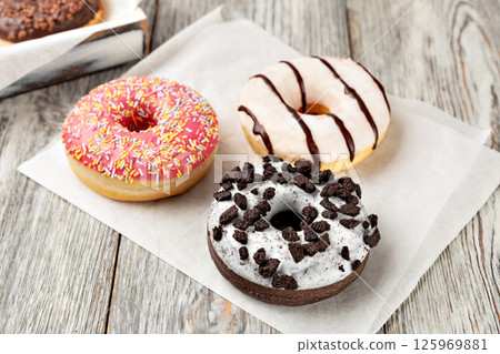 Delicious assorted donuts lying on white plate on wooden table 125969881