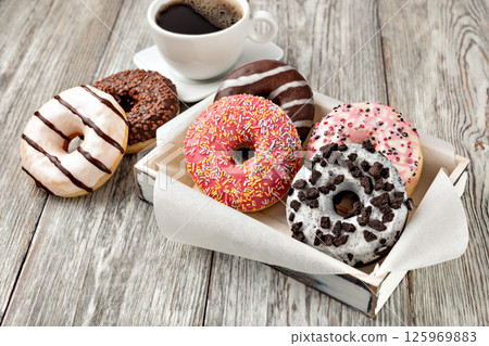 Delicious assorted donuts lying on white plate on wooden table Delicious assorted donuts lying on white plate on wooden table 125969883