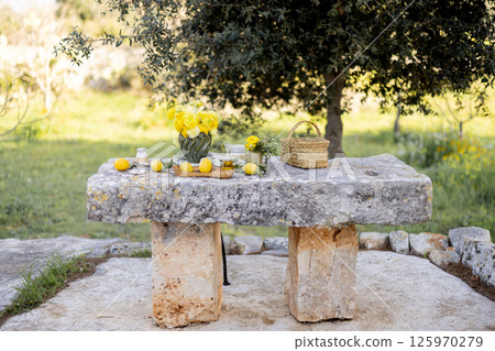 Stone table with lemons and flowers 125970279