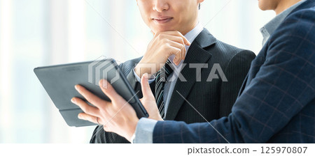 Two male businessmen having a meeting using a tablet 125970807