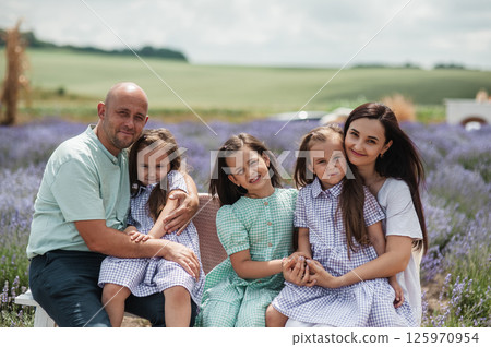 A family dressed in festive clothes is spending time in a lavender field. A family dressed in festive clothes is spending time in a lavender field. 125970954