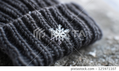 Intricate snowflake detail resting momentarily on winter accessory 125971107