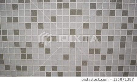 a close-up view of a tiled surface, featuring a pattern of small square tiles in varying shades of gray. The arrangement includes both light and dark tiles, creating a visually appealing checkerboard  125971397