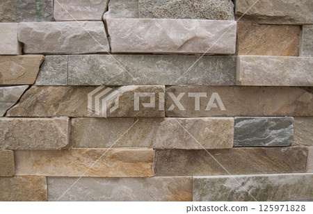 Beautiful beige structural stone wall of the ancient building consists of small bricks. Beautiful beige structural stone wall of the ancient building consists of small bricks. 125971828