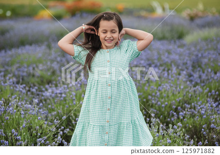 A little girl fixes her hair on a lavender field. 125971882
