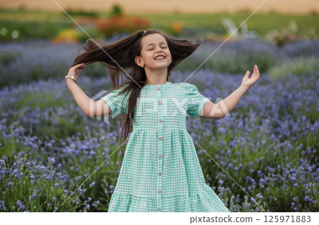 A little girl fixes her hair on a lavender field. 125971883