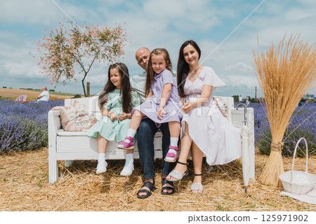 Resting in a lavender field. Family with two daughters and young parents on a lavender field. Resting in a lavender field. Family with two daughters and young parents on a lavender field. 125971902