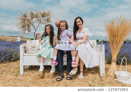 Children with their parents are resting on a lavender field. 125971903