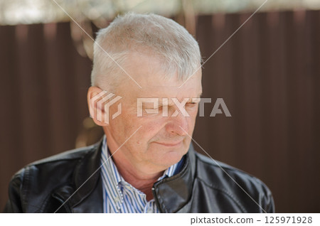 A pensioner dressed in a shirt and leather black jacket went for a walk. The old man is smiling sincerely. A pensioner dressed in a shirt and leather black jacket went for a walk. The old man is smiling sincerely. 125971928
