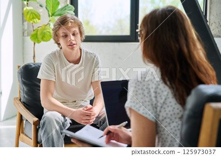 Teenage boy talking to female professional psychologist counselor therapist 125973037