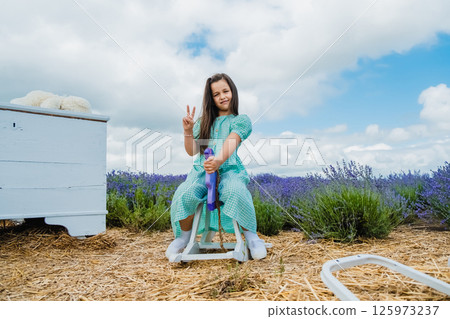A cute girl on a wooden toy rocking horse in a lavender field. A cute girl on a wooden toy rocking horse in a lavender field. 125973237