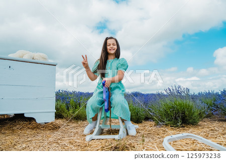 A cute girl on a wooden toy rocking horse in a lavender field. A cute girl on a wooden toy rocking horse in a lavender field. 125973238