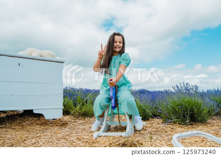 Wooden rocking horse toy in a lavender field. Beautiful girl riding a toy rocking horse.  125973240