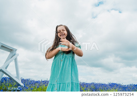 A cheerful girl of European appearance is jumping merrily in a beautiful field. 125973254