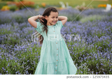 A little girl fixes her hair on a lavender field. 125973435