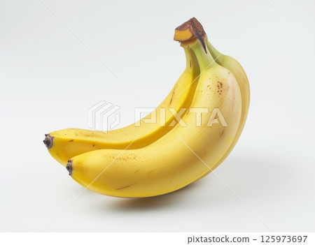 Two ripe yellow bananas with brown spots, slightly curved, lie together on a white background 125973697