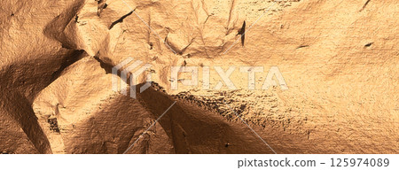 Bronze metallic foil texture with creased, crumpled surface. Shiny, reflective background in golden 125974089