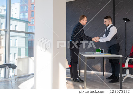 Two Caucasian men shaking hands. Interview or business meeting. Two Caucasian men shaking hands. Interview or business meeting. 125975122