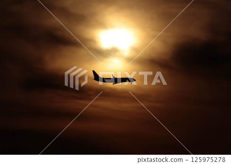 The moment when the sunset and the airplane overlap 125975278