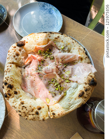 Classic pizza with sliced meat and cheese, melted mozzarella. Traditional pizza in restaurant 125975856