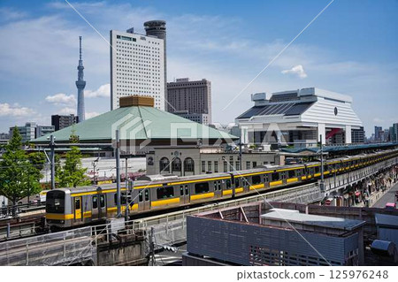 The Sobu Line runs with the Ryogoku Kokugikan, Tokyo Skytree, and Edo-Tokyo Museum in the background The Sobu Line runs with the Ryogoku Kokugikan, Tokyo Skytree, and Edo-Tokyo Museum in the background 125976248