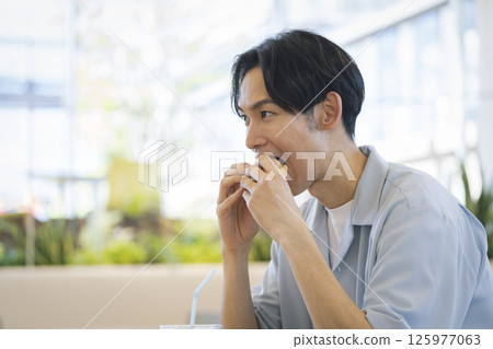 Young man eating hamburger, profile 125977063