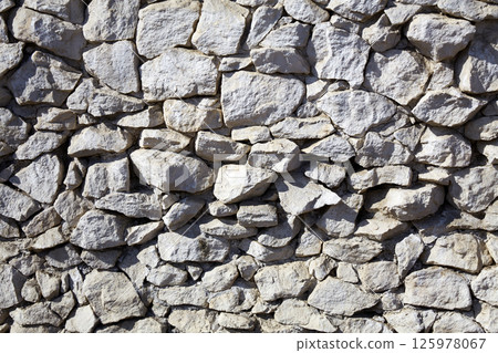 Natural stone wall showcases varied textures and colors in an outdoor setting during daylight hours Natural stone wall showcases varied textures and colors in an outdoor setting during daylight hours 125978067
