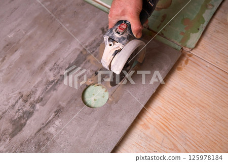 Skilled hands cut granite tiles during repair work in a home workshop in daylight Skilled hands cut granite tiles during repair work in a home workshop in daylight 125978184