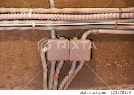 The electrical wires in the protective corrugated cable tube and the junction box are neatly laid on the ceiling 125978199