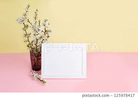 A bouquet of flowering plum branches in a vase and a photo frame 125978417