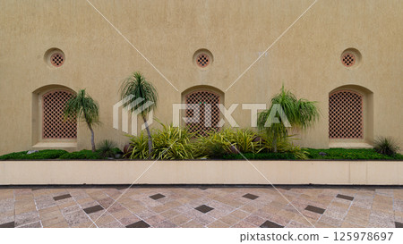 Decorative wall with lattice design and lush greenery in an urban setting during daytime Decorative wall with lattice design and lush greenery in an urban setting during daytime 125978697