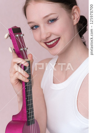 Closeup of beaming young female musician got ukulele in hand, looking straight at camera with big smile, radiant expression that says she's feeling inspired. Caucasian woman, aged 18, true inspiration Closeup of beaming young female musician got ukulele in hand, looking straight at camera with big smile, radiant expression that says she's feeling inspired. Caucasian woman, aged 18, true inspiration 125978700
