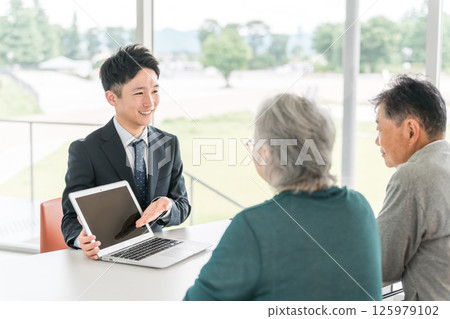 商人向老年夫婦解釋、提議、指導和推薦（銀行工作人員、資產管理、股票、投資、保險） 125979102