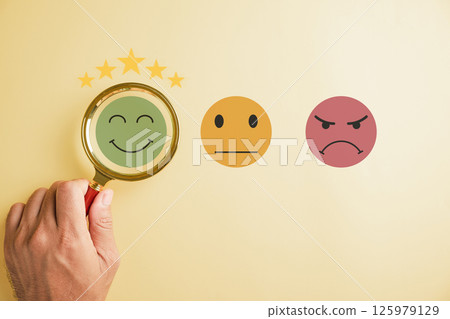 Magnifying glass held by hand selects happy smiley face icon among emotions. Good feedback rating, positive customer review. Experience, satisfaction survey, mental health concept. satisfaction. Magnifying glass held by hand selects happy smiley face icon among emotions. Good feedback rating, positive customer review. Experience, satisfaction survey, mental health concept. satisfaction. 125979129