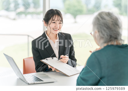 A businesswoman explaining, proposing, guiding and recommending to an elderly couple A businesswoman explaining, proposing, guiding and recommending to an elderly couple 125979389